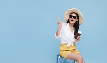 Happy smiling Asian woman dressed in summer clothes and wearing hat with luggage enjoying their...