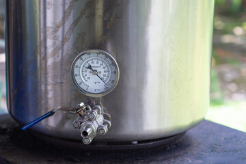 Close-up of alcohol thermometer on craft beer tank. Selective focus. Home brewing process.