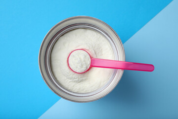 Can of powdered infant formula with scoop on color background, top view. Baby milk