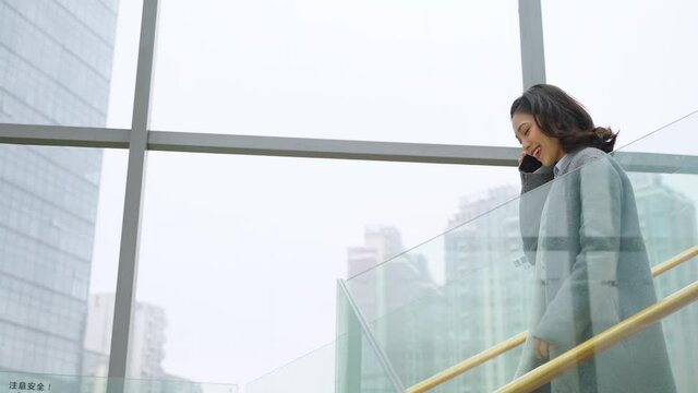 young asian woman talking on the phone walking down stair