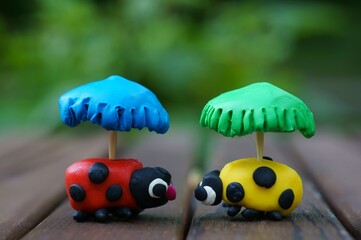 Figurines of two ladybirds with umbrellas made of plasticine.