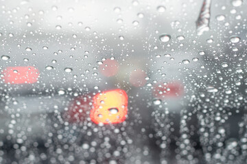 Safety driving car in rainy season concept. Rain drop falling in front of windshield window on road in heavy traffic in big city