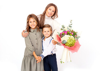 Cute boy and girl children and mother with a bouquet of flowers on a white background in the studio