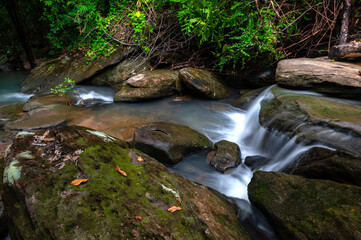 Naklejka na ściany i meble Native picturesque waterfall,Small Waterfall in deep forest,Ubon Ratchathani province,Thailand.leaf moving low speed shutter blur.