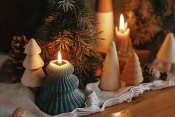 Christmas advent. Stylish burning christmas candles, pine trees and cones modern decorations on rustic old wooden background in evening scandinavian room. Atmospheric moment - Powered by Adobe