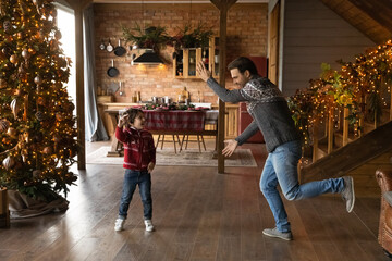 Playful happy young father having fun with adorable energetic small kid son, dancing or joking near...