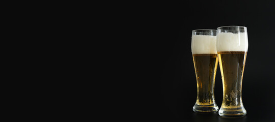 Two frosty glasses of cold golden beer with bubbles on the black background. Free space for text,...