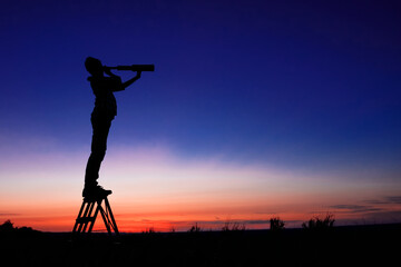 Child looks at the stars through a telescope. A teenager boy looks at the night sky through a spyglass against the backdrop of a sunset while in the field. - obrazy, fototapety, plakaty
