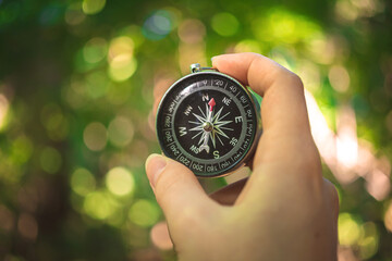 Traveler holding the compass in hand, forest background photo