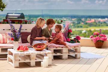 cheerful kids, siblings having fun, playing together on pallet lounge furniture at the rooftop...