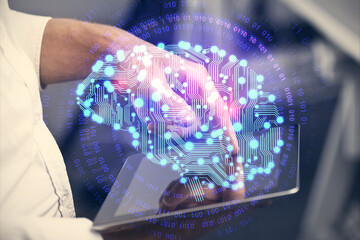Double exposure of man's hand holding and using a digital device and brain hologram drawing. Data concept.