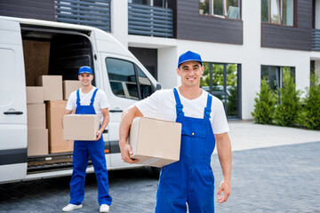 Two removal company workers unloading boxes from minibus into new home