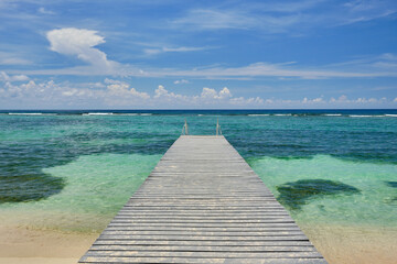 Sandy wooden dock stretches out into the crystal clear and warm waters of the Carribean  in the Cayman Islands