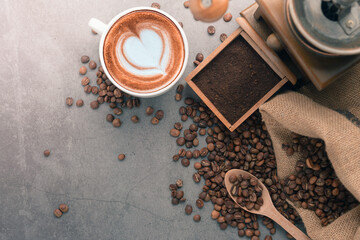 Cup of coffee latte with heart shape and coffee beans on old wooden background, copy space for text.