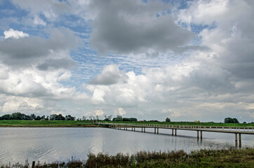 bridge for pedestrians and cyclist across a secondary channel of the river IJssel near Zwolle, The Netherlands under a dramatic sky