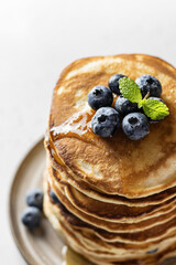 Stack of pancakes with syrup and blueberry on white background
