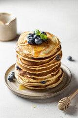 Stack of pancakes with syrup and blueberry on white textured background