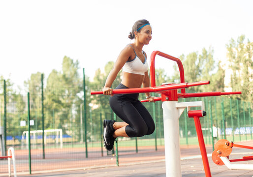 Young athletic woman working out on workout ground with exercise equipment outdoor