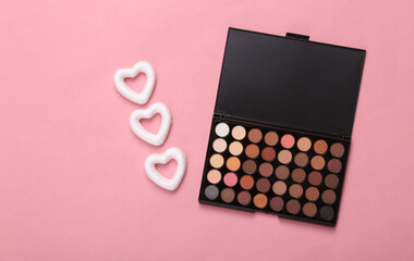 Makeup palette with hearts on pink background. Minimal beauty layout