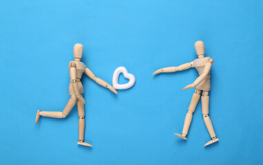 Puppet gives his heart to his beloved on blue background. Love concept