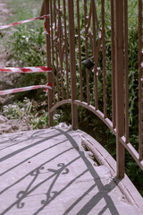 A small bridge over the river with a barrier tape. Red and white tape prohibits passage over the bridge. Summer afternoons. Selective focus.