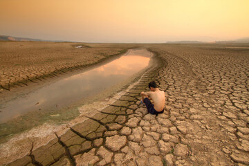 Children sitting near dry river with hopeless. Drought impact lake is drying. World Climate change and Global warming problem - obrazy, fototapety, plakaty