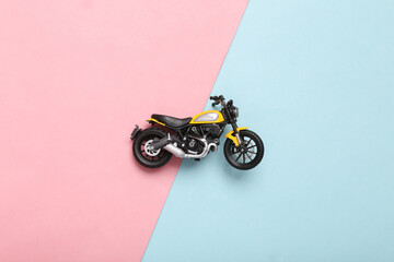 Toy motorcycle model on pink blue background. Top view