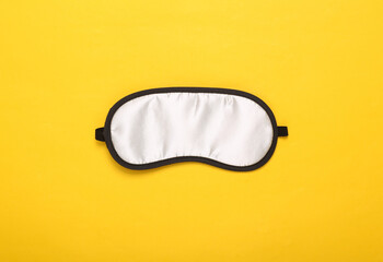 Fototapeta premium Sleep mask on yellow background. Top view, flat lay. Concept of vivid dreams. Accessories for sleep. Minimal style.
