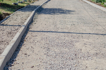 Construction of a new road and sidewalk. The roadway and walkway are filled with compacted crushed stone. Ready to be covered with asphalt or concrete. Repair and construction work.
