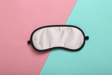 Fototapeta premium Sleep mask on pink blue background. Top view, flat lay. Concept of vivid dreams. Accessories for sleep. Minimal style.