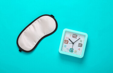 Sleep mask and alarm clock on a blue background. Insomnia concept. Top view