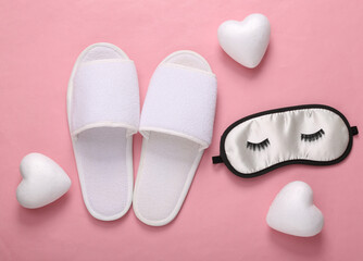 Sleeping mask with eyelashes, hearts and slippers on a pink background. Sweet, love dreams. Top view