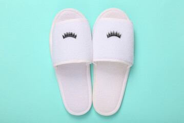 Sleeping slippers with eyelashes on a blue background. Minimal layout