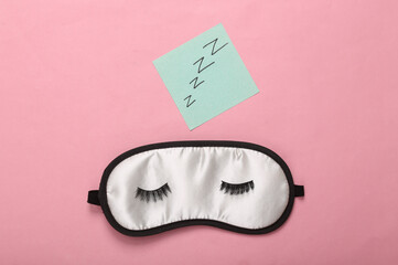 Sleeping mask with eyelashes on a pink background. Healthy sleep concept