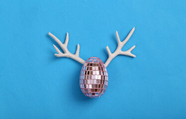 Creative Easter layout. Mirror egg with antlers on blue background. Party concept