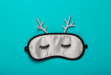 Sleeping mask with deer antlers on blue background. Minimal, creative layout