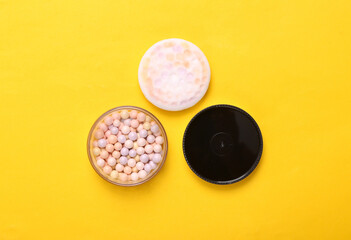Balls of powder on a yellow background. Cosmetics. Top view