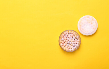Balls of powder on a yellow background. Cosmetics. Top view