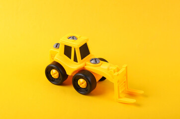 Toy forklift on yellow background