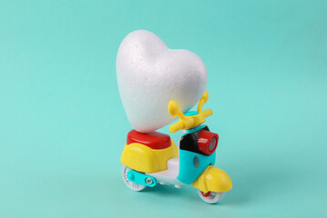 Toy scooter with heart on blue background. Love, Delivery concept