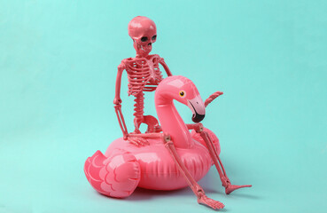 Skeleton with pink inflatable flamingo on blue background. Halloween party concept