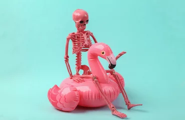 Fotobehang Skeleton with pink inflatable flamingo on blue background. Halloween party concept © splitov27