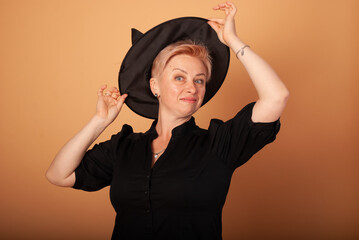 charming woman vamp witch holds a hat near her head for Halloween