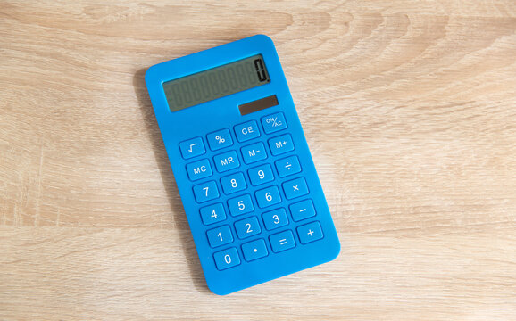 Blue calculator on a wooden table. Top view