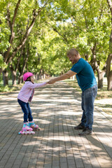 Obraz premium dad teaches daughter to roller skate.