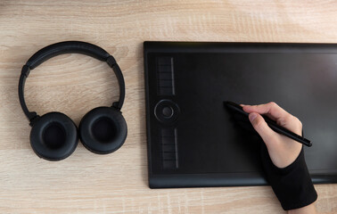 Female hand works with a graphics tablet on the table. Designer or retoucher work