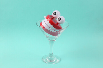 Toy jaw in cocktail glass on blue background. Fresh idea. Minimal party concept, creative layout