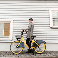 Young beautiful girl hipster in fashionable casual outfit with a plaid shirt with a yellow bicycle...