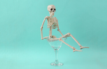 Cocktail glass with skeleton on blue background. Fresh idea. Minimal party concept, creative layout