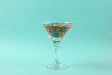 Cocktail glass with colored sprinkling on blue background. Fresh idea. Minimal easter concept, creative layout